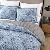 A blue and white comforter featuring an intricate paisley pattern, elegantly draped across a bed.